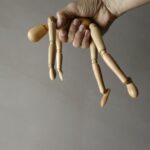 person holding brown wooden mannequin