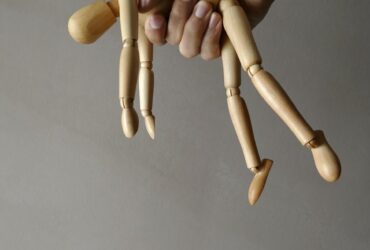 person holding brown wooden mannequin