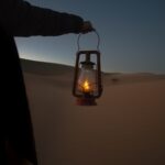 person holding red kerosene lantern
