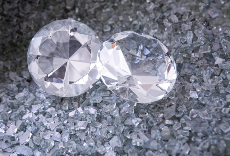 two diamonds sitting on top of a pile of crushed glass