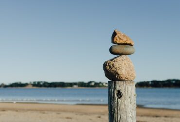 rock balancing on wooden post near body of water