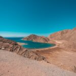 brown mountain near blue sea under blue sky during daytime