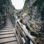 brown wooden bridge in the middle of two mountain