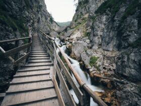 brown wooden bridge in the middle of two mountain