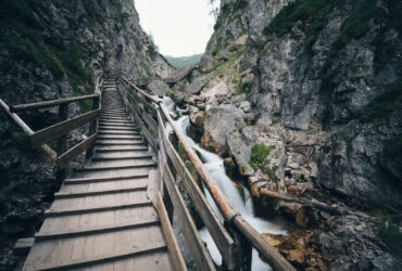 brown wooden bridge in the middle of two mountain