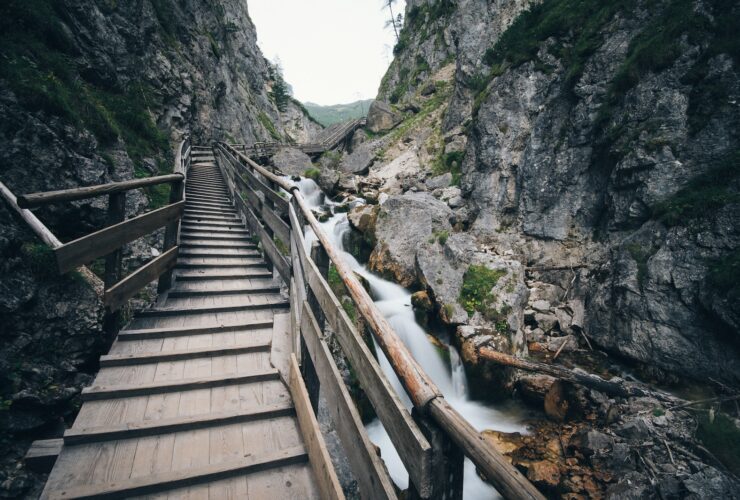brown wooden bridge in the middle of two mountain