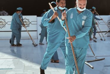a group of men in blue uniforms with brooms