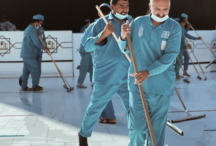 a group of men in blue uniforms with brooms