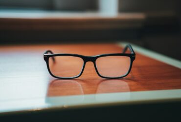 a pair of black glasses on a wooden surface