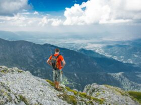 man standing on peak front of mountain at daytime