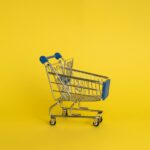 Isolated shining metal shopping trolley without anything located separately on yellow background