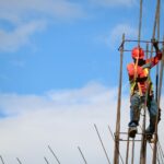 man wearing red hard hat hanged on brown rebar bar