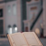 High angle of opened Koran book placed on stone stand in yard of ancient mosque