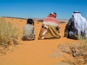 a couple of people sitting on top of a sandy field