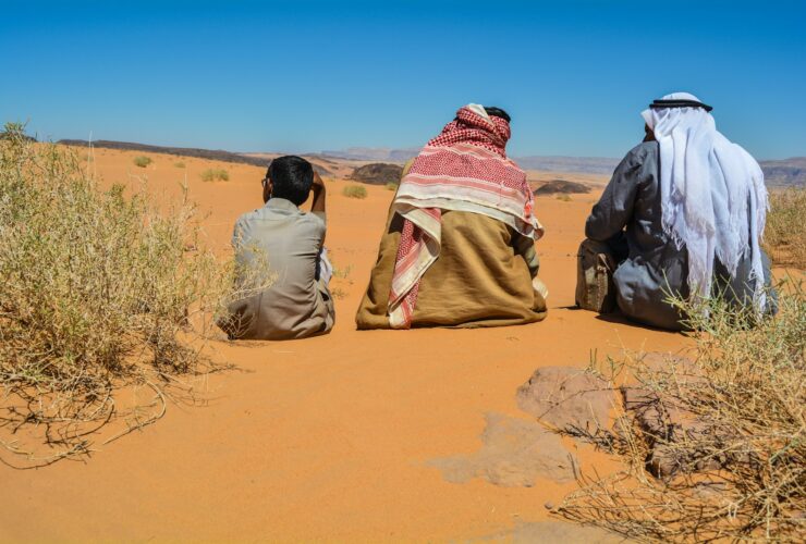 a couple of people sitting on top of a sandy field