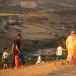 Unrecognizable people walking on hilltop with kids