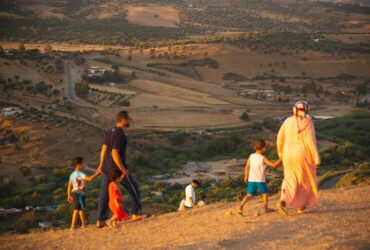 Unrecognizable people walking on hilltop with kids