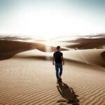 man walking through desert area
