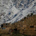 brown concrete building near snow covered mountain during daytime