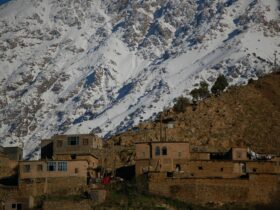 brown concrete building near snow covered mountain during daytime