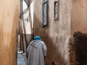 person wearing gray robe holding stick during daytime
