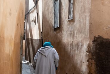 person wearing gray robe holding stick during daytime