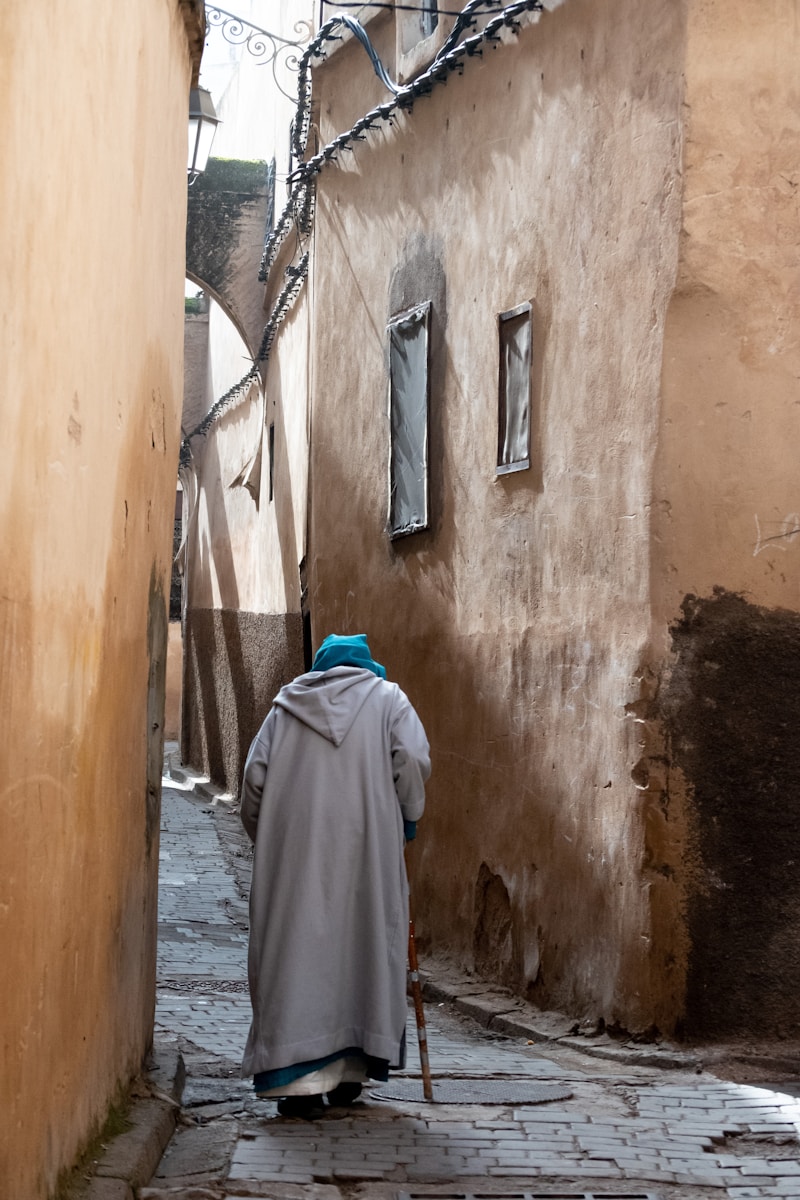 person wearing gray robe holding stick during daytime