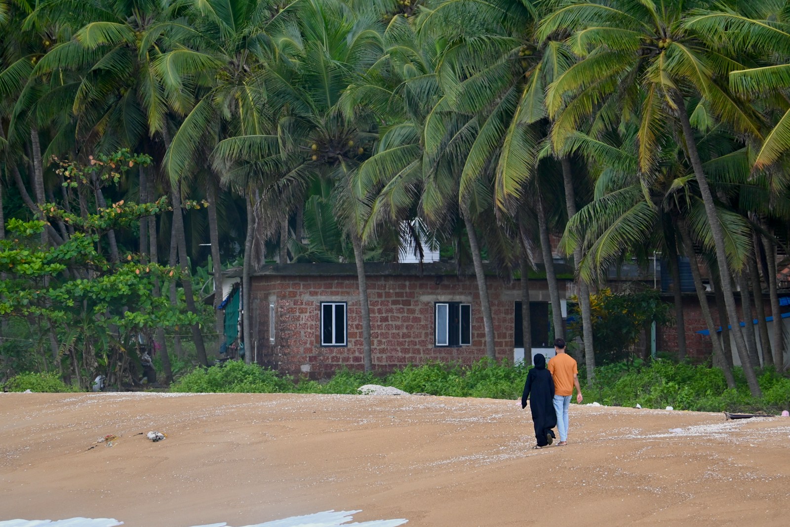 A person walking on a beach with palm trees in the background