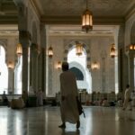 a man in a white robe is walking through a building