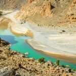 brown rocky mountain near blue lake during daytime