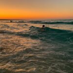 man surfing on sea waves during sunset