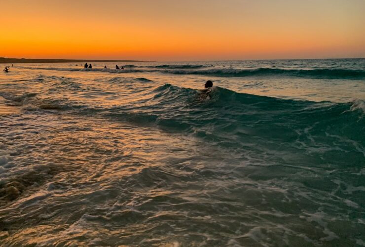 man surfing on sea waves during sunset