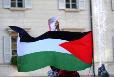 a person holding a flag in front of a building