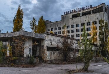 white concrete building near green trees under white clouds during daytime