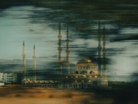 a building with a domed roof and towers with a body of water in the background