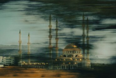 a building with a domed roof and towers with a body of water in the background