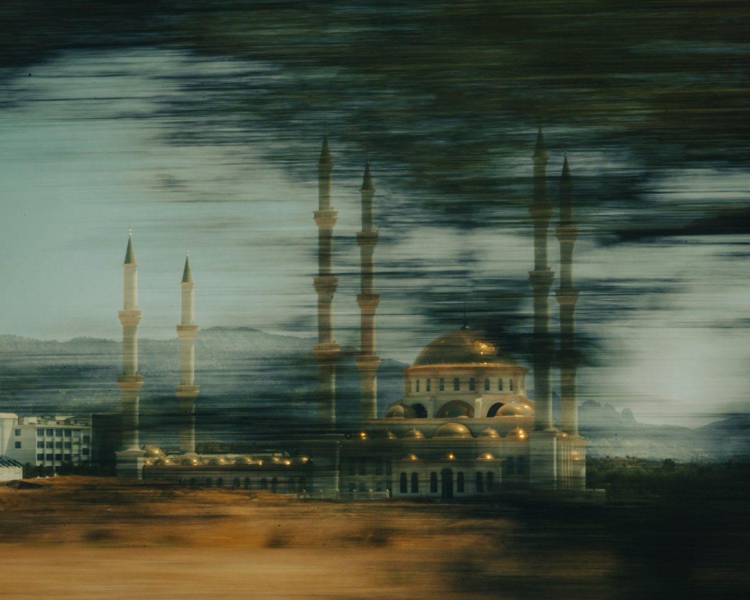 a building with a domed roof and towers with a body of water in the background