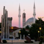 A mosque and fountain under a pink sunset.